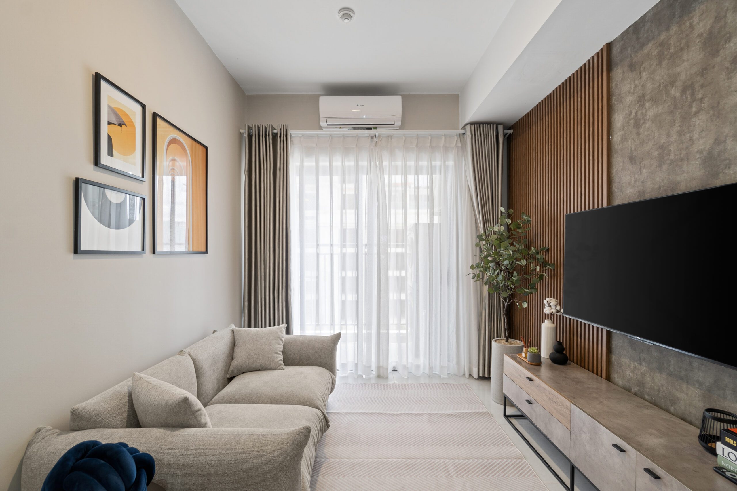 Phòng khách căn hộ Soho Residence với sofa kem và TV treo tường