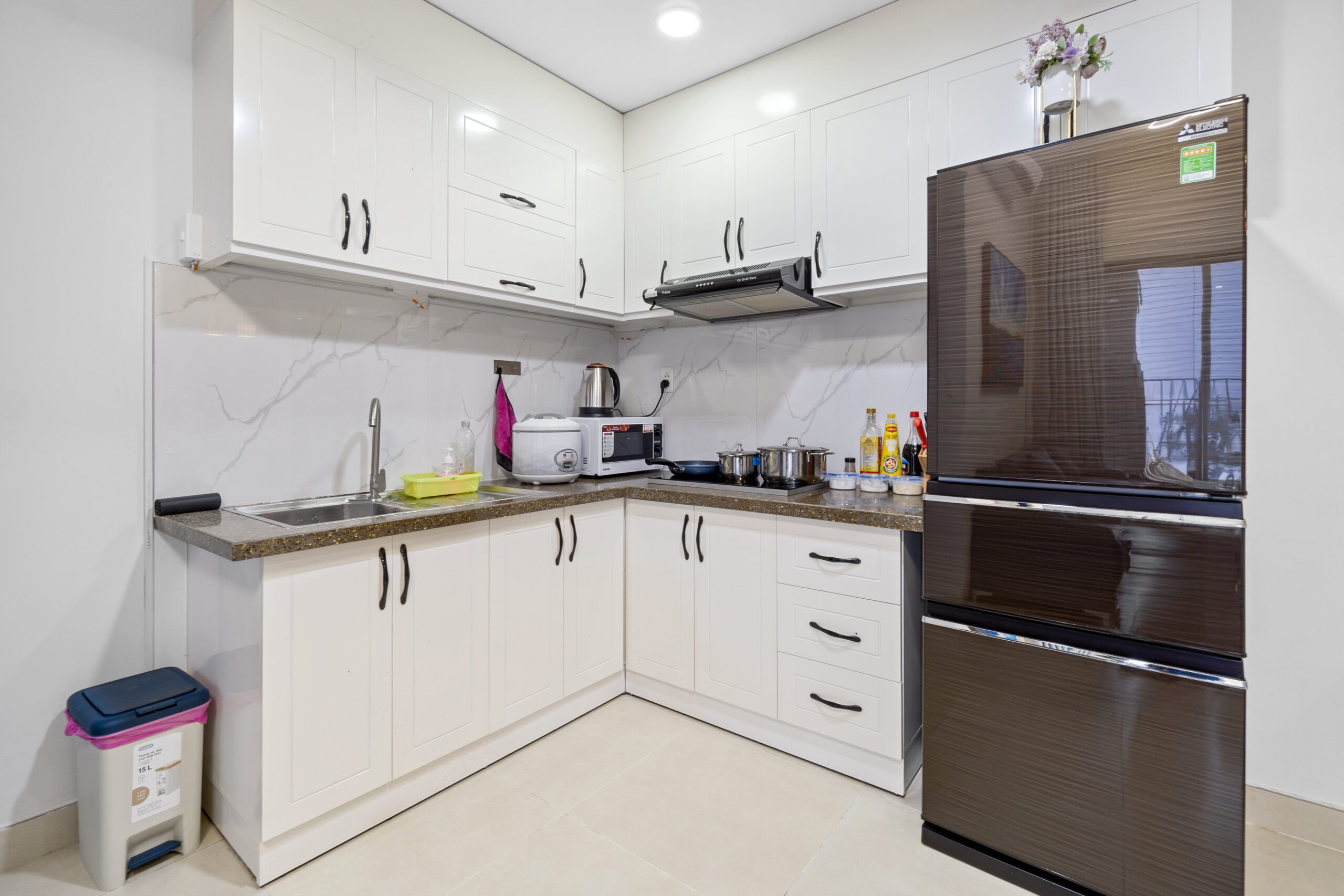 Bếp căn hộ Masteri Thảo Điền với tủ trắng và tủ lạnh đen