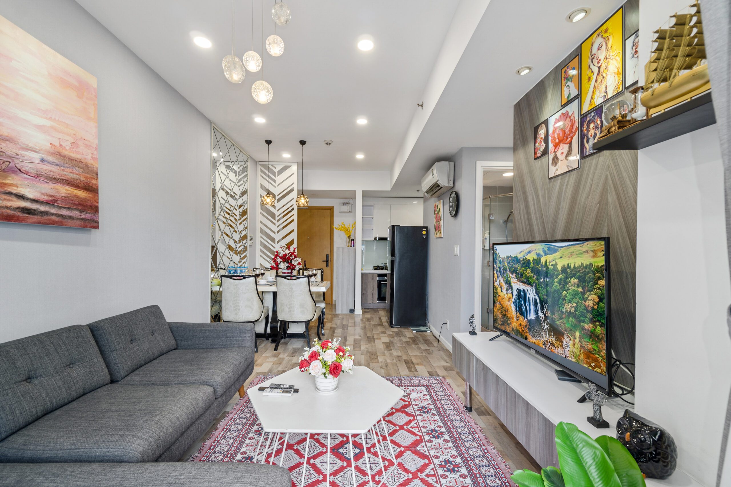 Phòng khách căn hộ Masteri với sofa xám dài và TV treo trên vách ốp