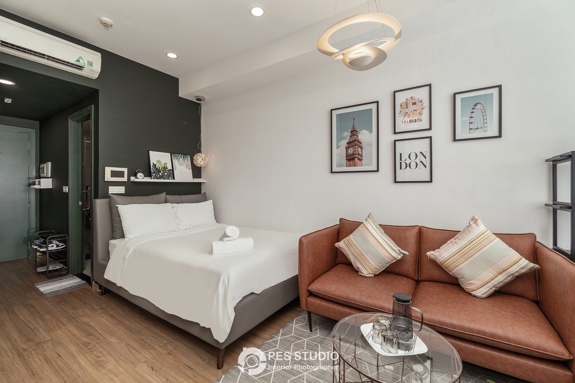 Studio River Gate với giường, sofa da nâu và tường treo tranh khung đen