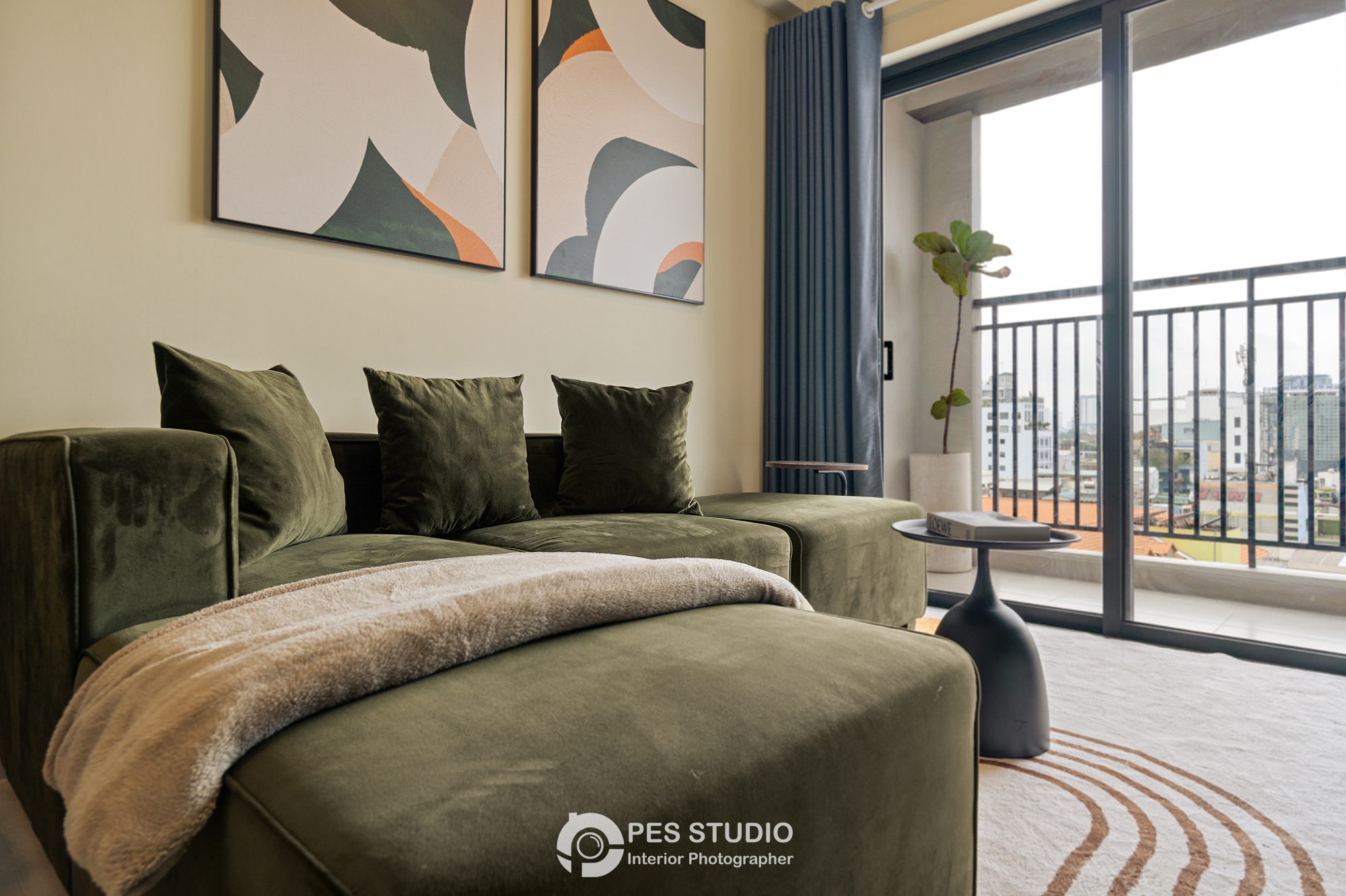 Sofa xanh rêu và gối tựa trong phòng khách căn hộ Soho Residence