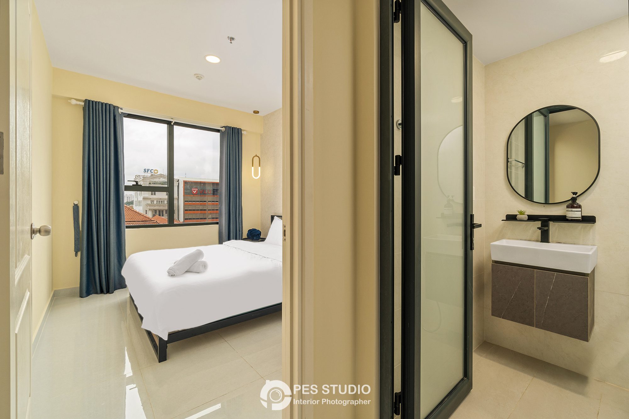 Phòng ngủ với khăn gấp trên giường và bàn lavabo phía sau