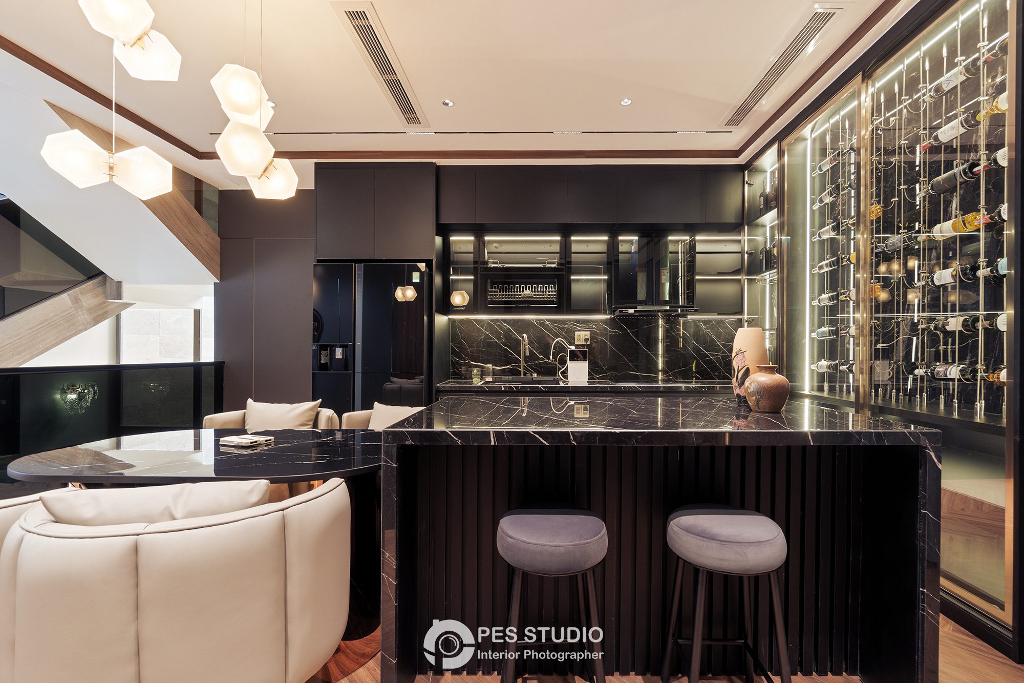 Quầy bar biệt thự với mặt đá, ghế bọc da và tủ rượu phía sau