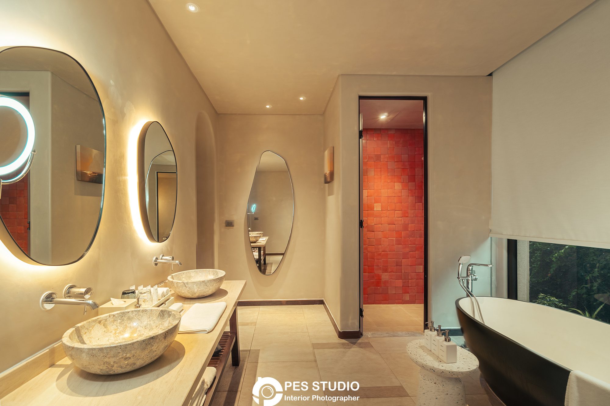 Phòng tắm resort với gương oval viền và hai chậu rửa đặt bàn