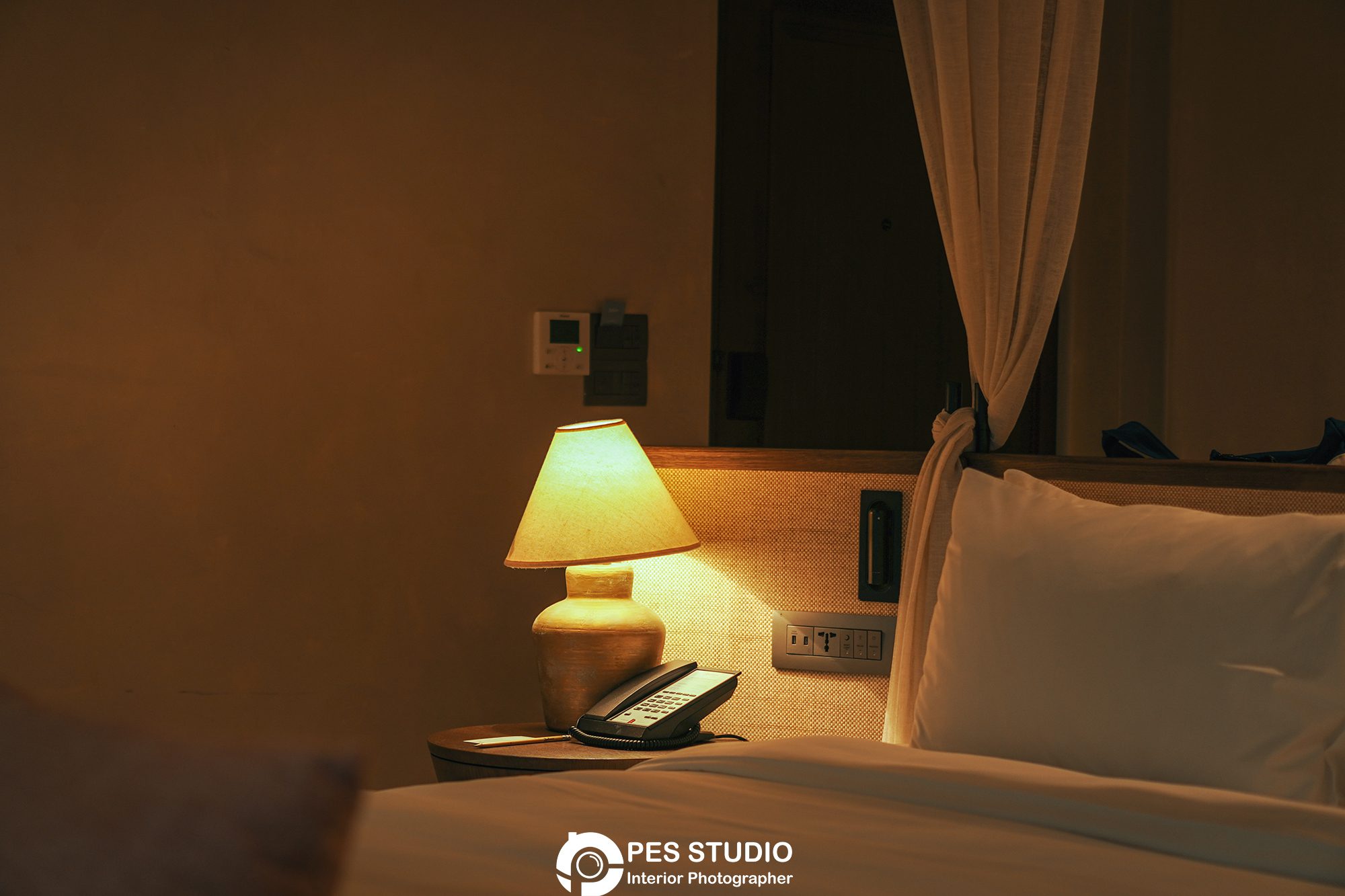Đèn bàn đầu giường và rèm voan trong phòng nghỉ resort