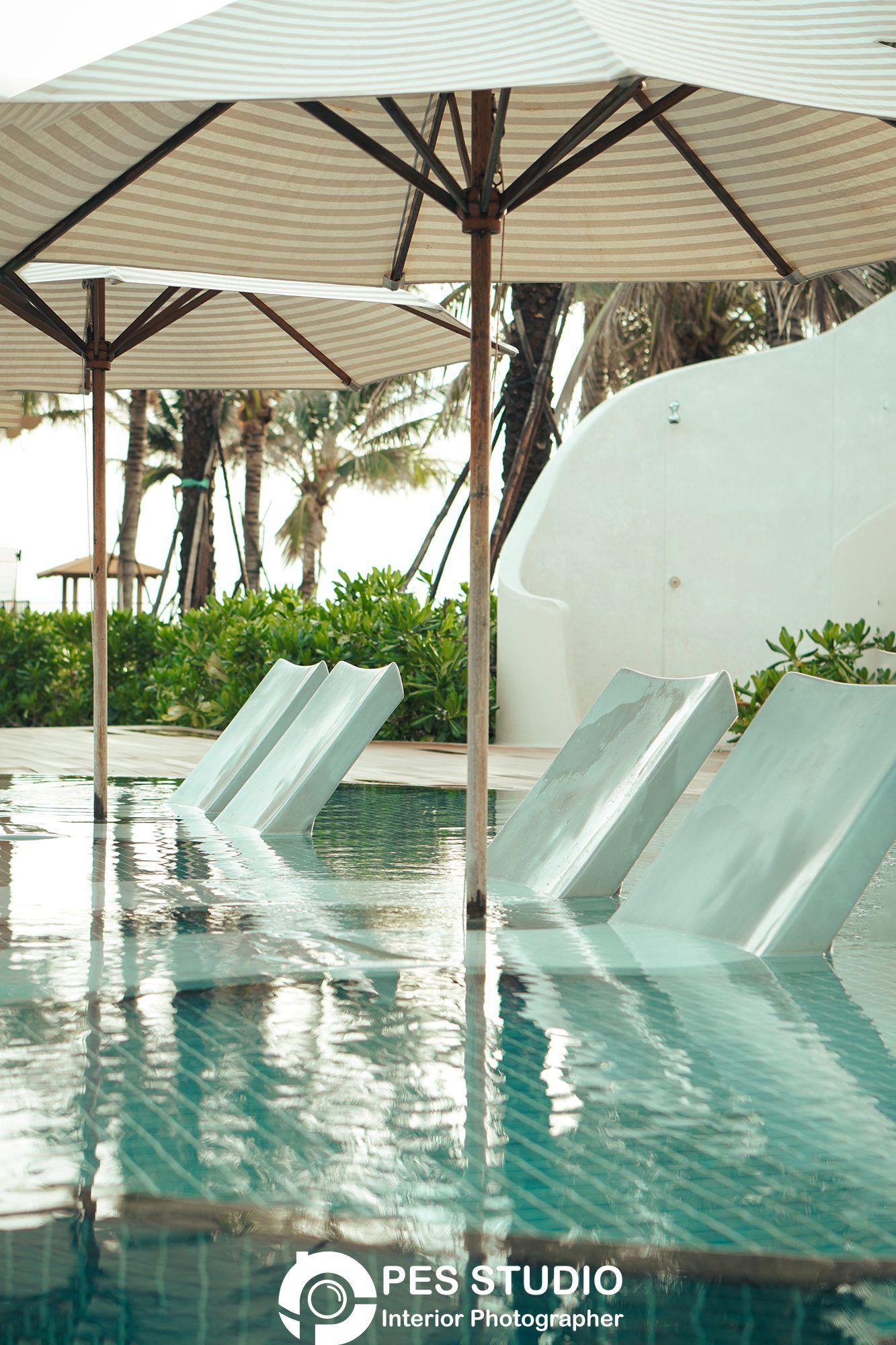 Ghế nằm trắng đặt sát mép hồ bơi resort Radisson