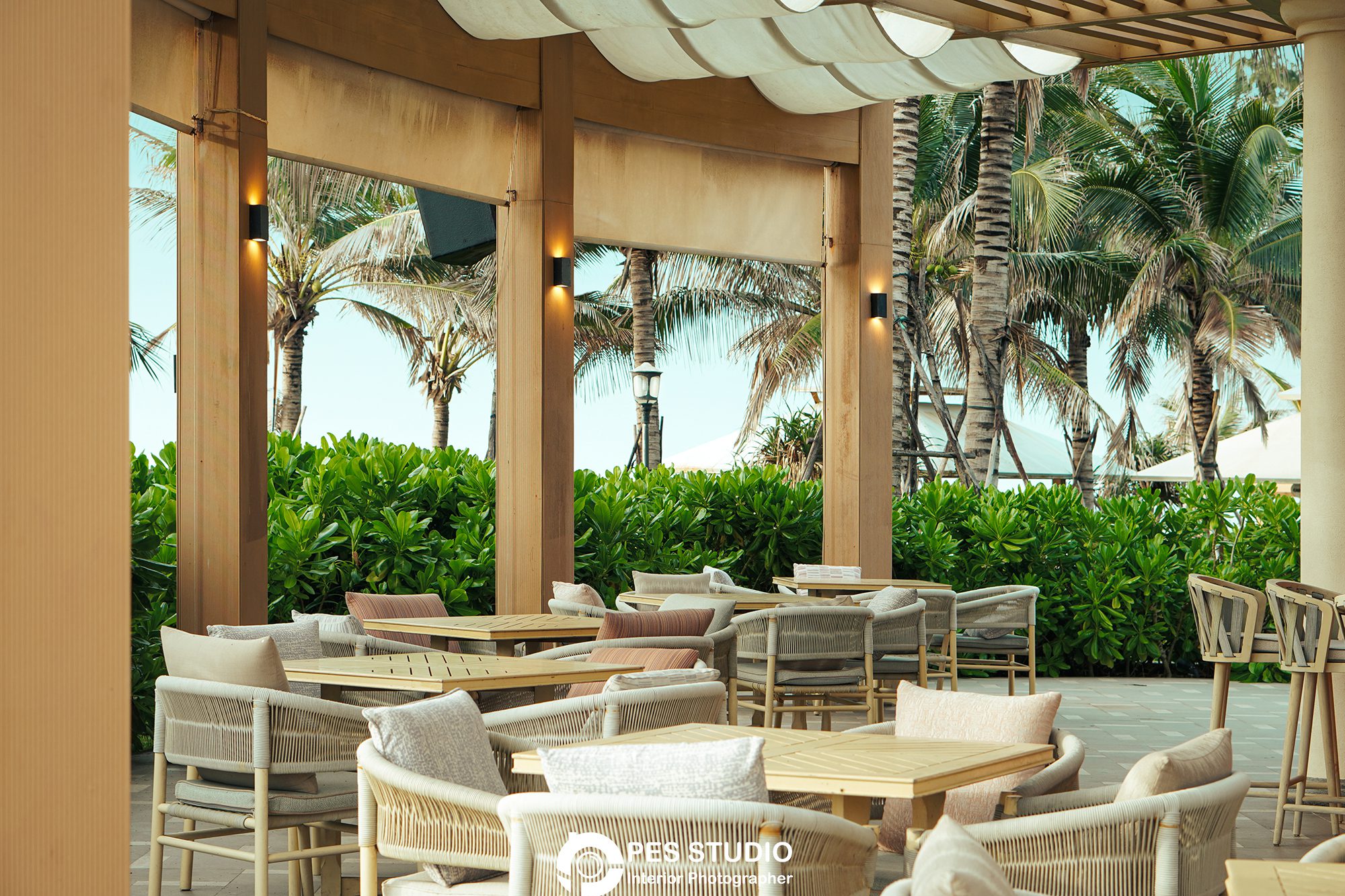 Khu ngồi ngoài trời resort với sofa mây dưới mái hiên