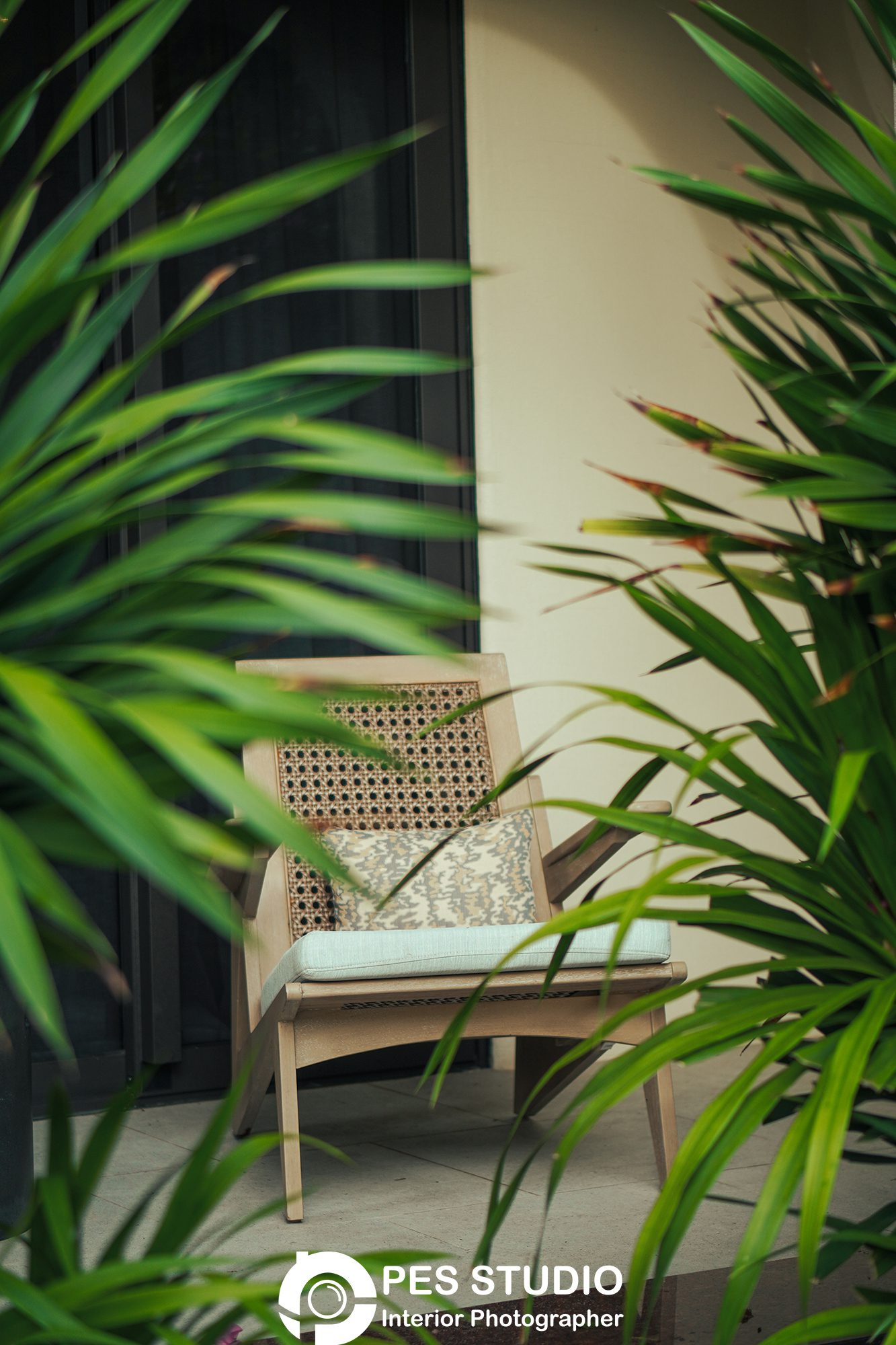 Ghế mây đặt trước mảng cây xanh trong khuôn viên resort