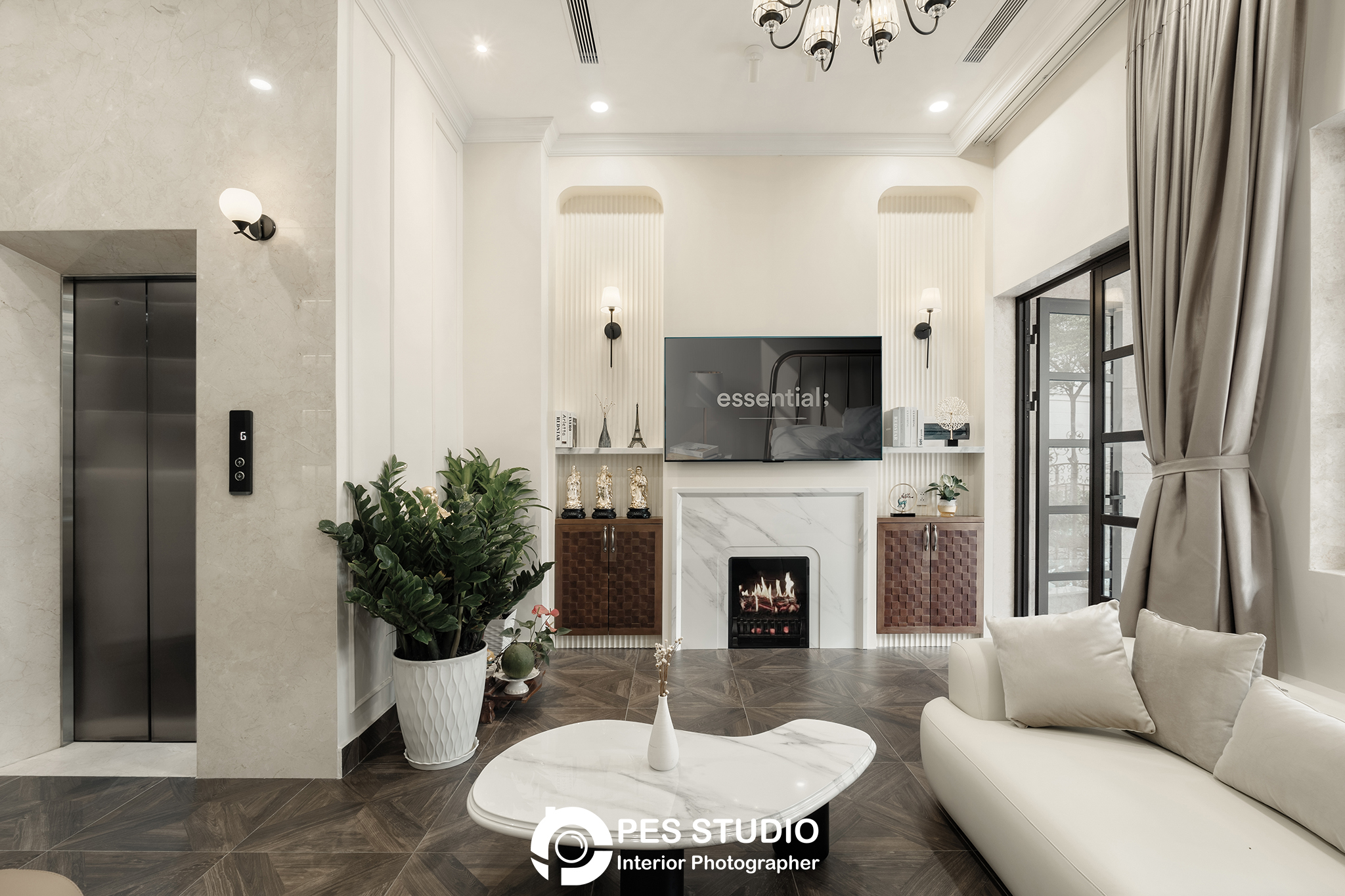 Phòng khách nhà phố CityLand với sofa kem, đèn chùm và cầu thang phía sau