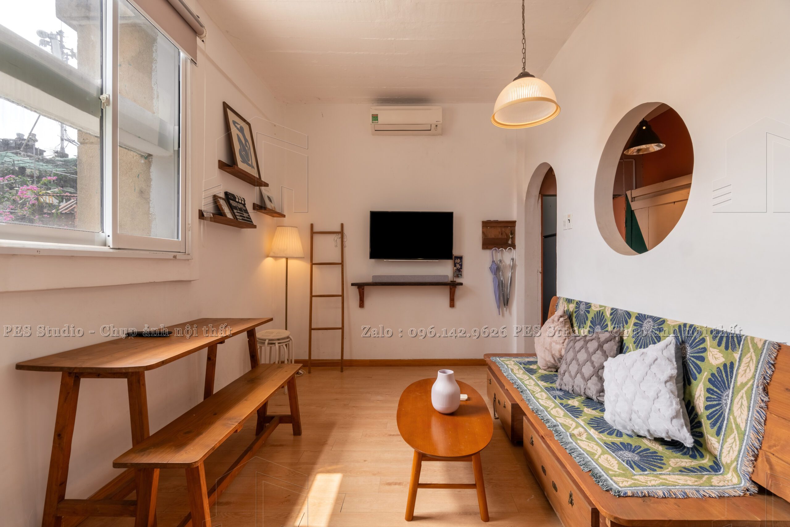 Khu bàn ăn homestay với ghế đệm và gương tròn treo tường