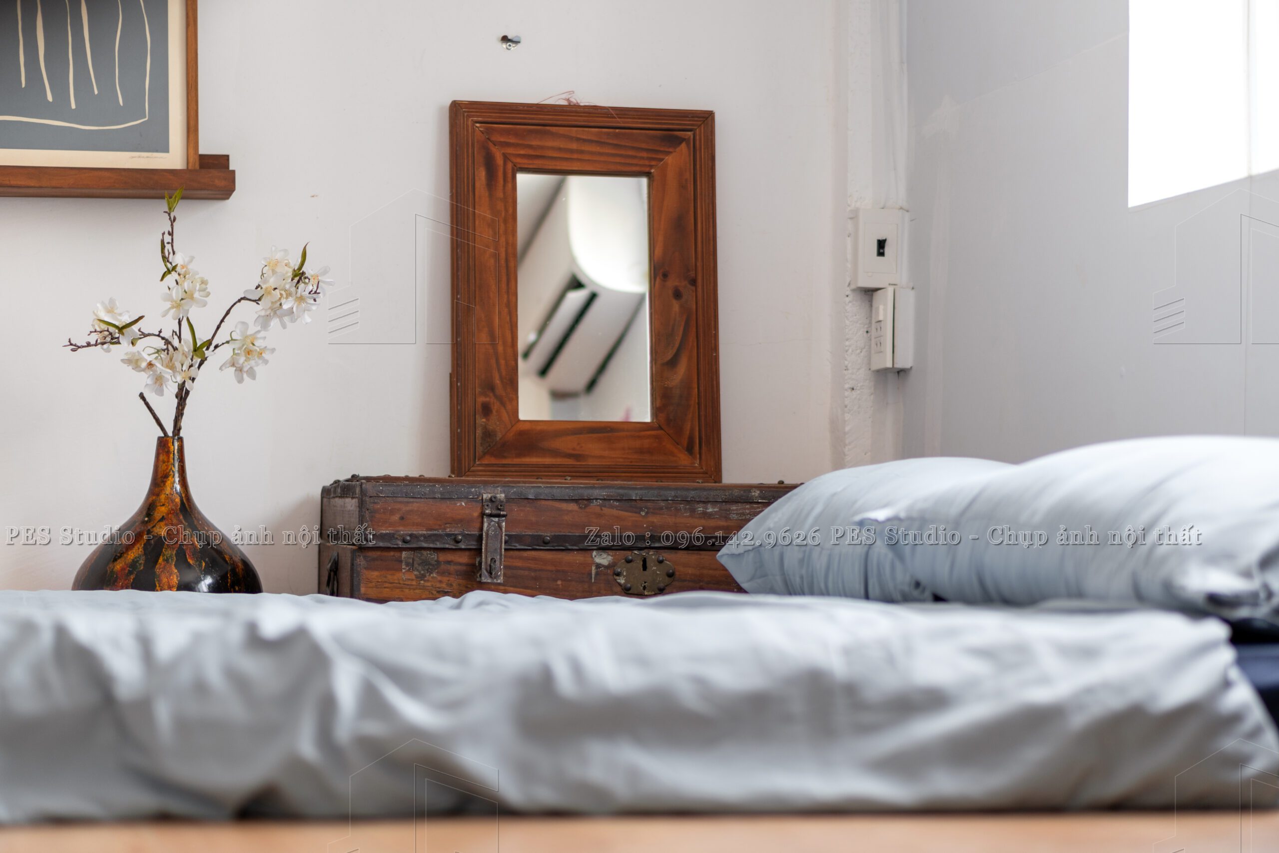 Giường và gương gỗ cổ đặt cạnh cửa sổ homestay Nguyễn Huệ