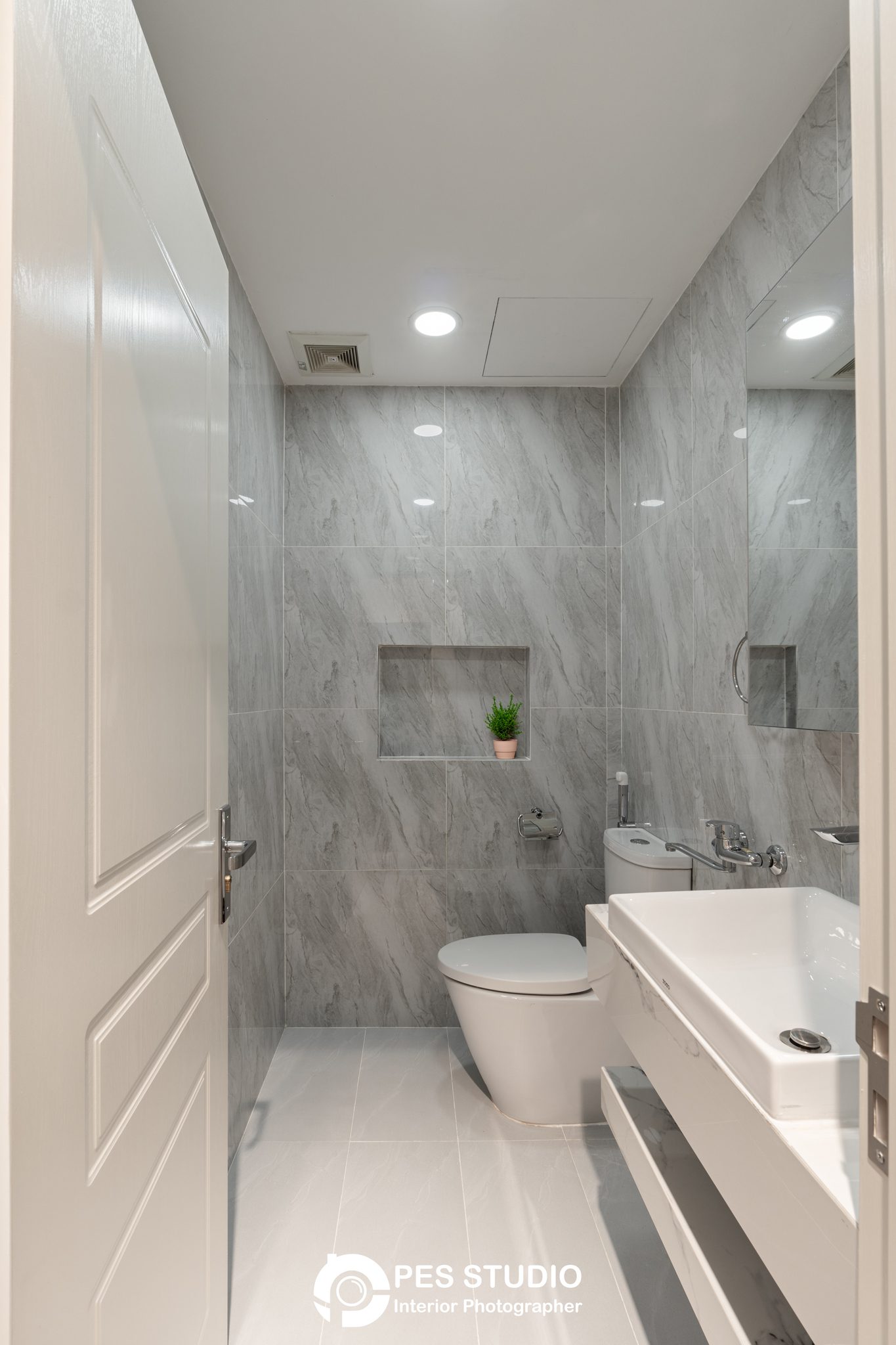 Phòng tắm căn hộ Dream Palace ốp đá vân xám với hốc để đồ