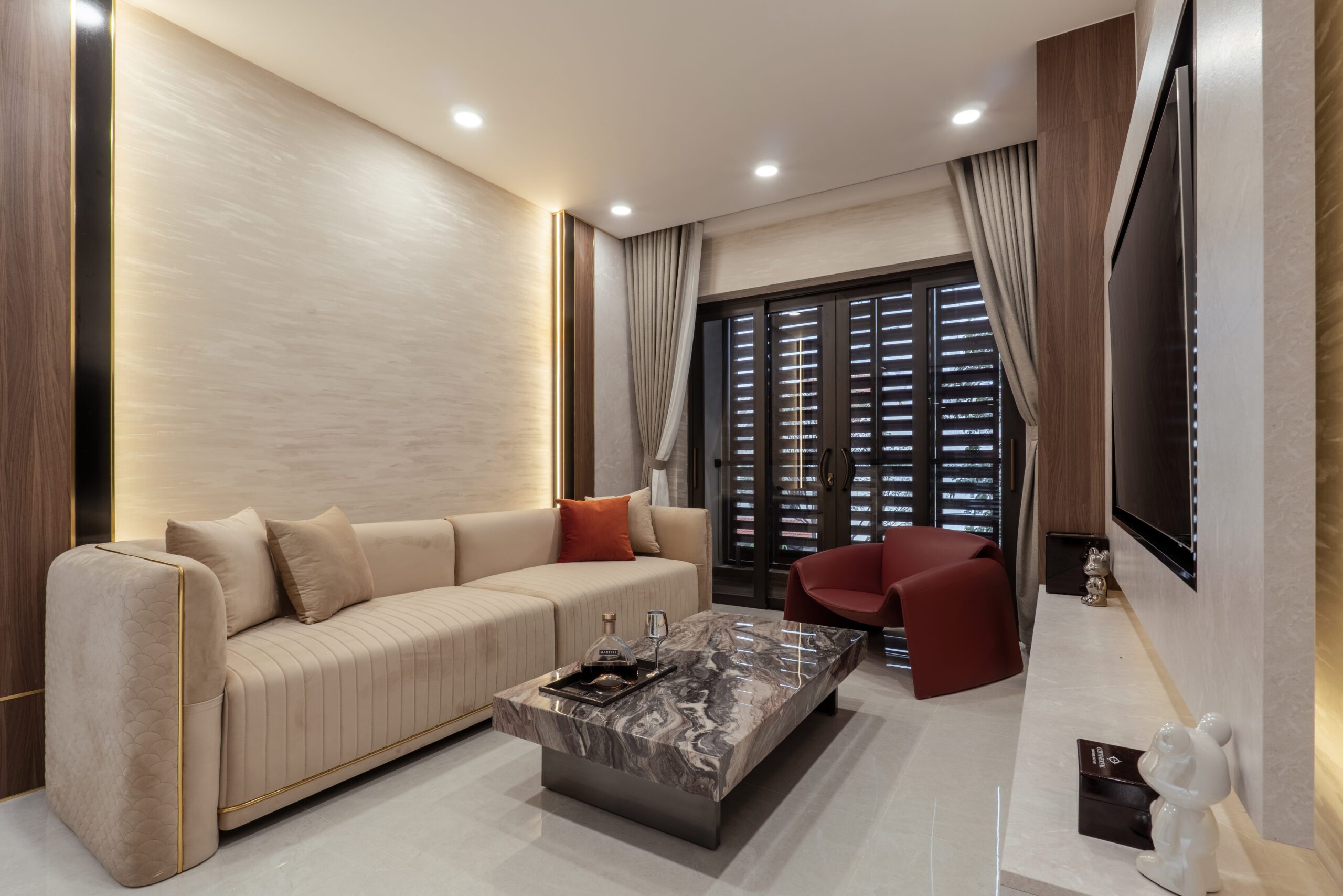 Phòng khách nhà phố Trần Phú với sofa kem và ghế bành đỏ đô