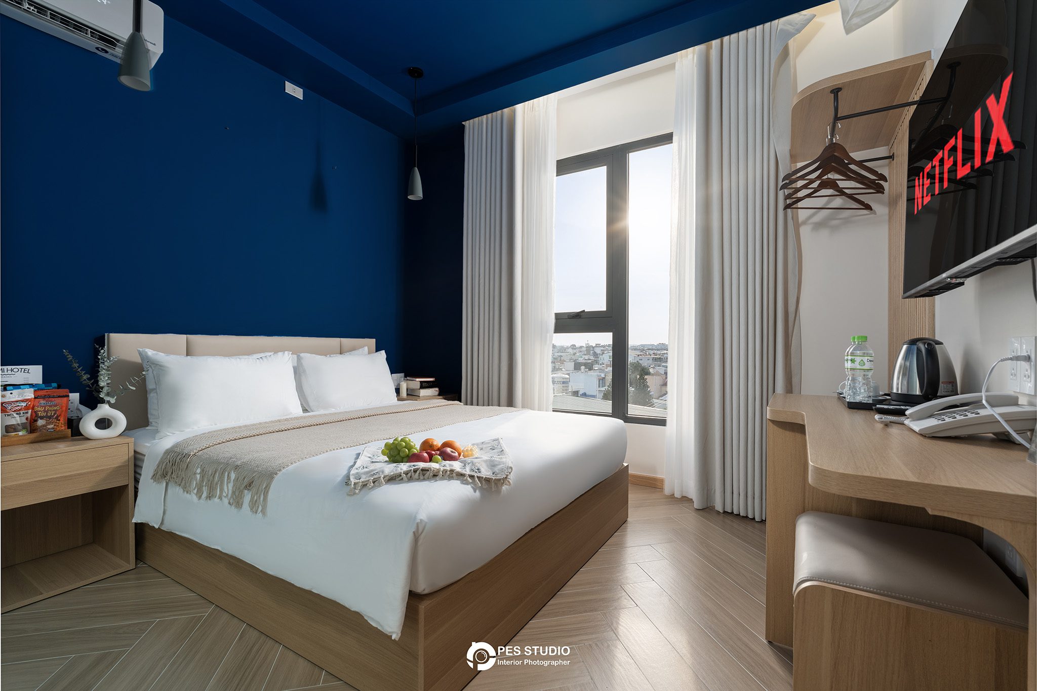 Phòng nghỉ Lumi Riverside với tường xanh navy và TV treo tường