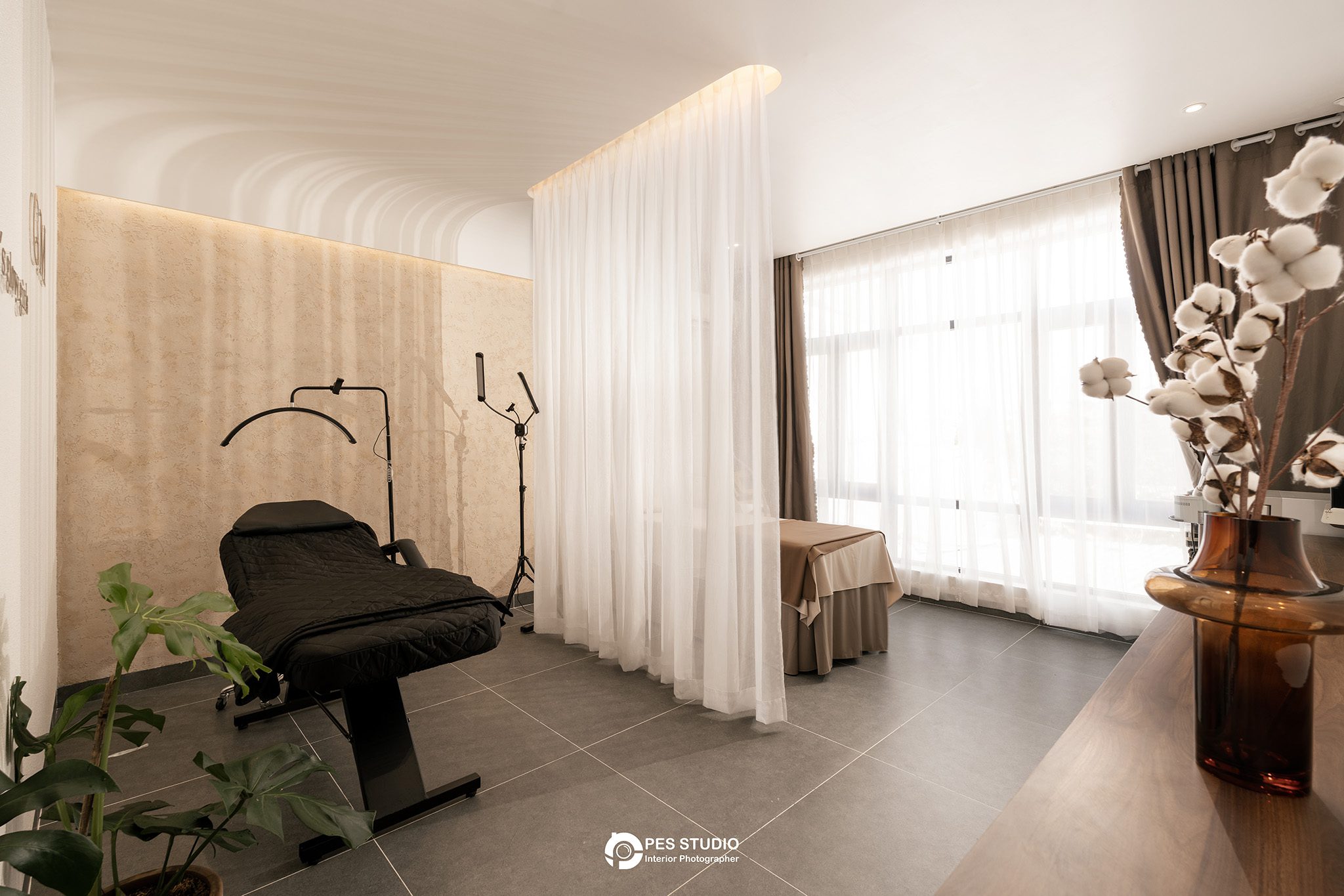 Phòng trị liệu với giường spa, rèm voan trắng và cửa sổ lấy sáng