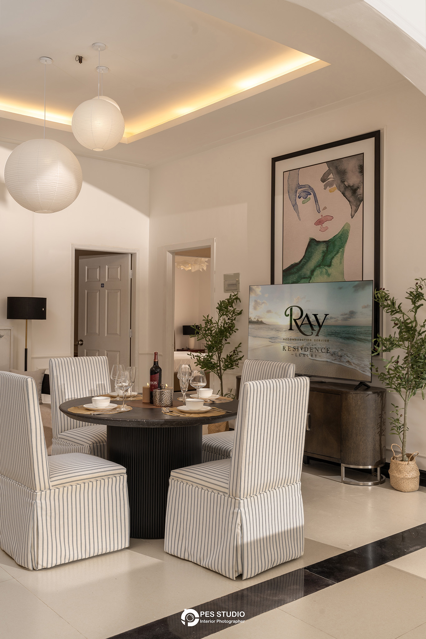 Bàn ăn villa An Phú Compound nhìn qua khung cửa với ghế bọc sọc