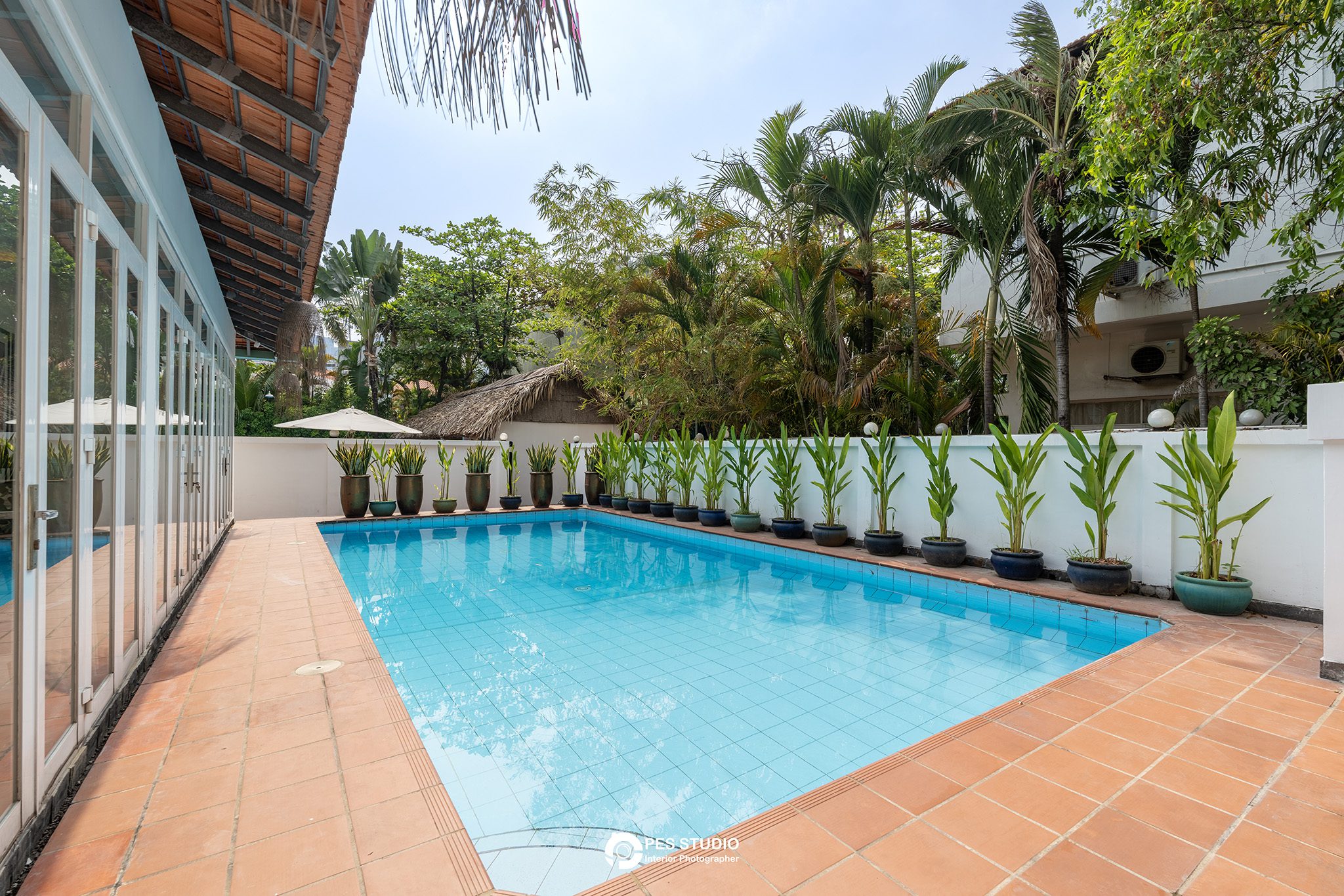 Hồ bơi villa An Phú Compound với sàn gỗ và hàng cây nhiệt đới
