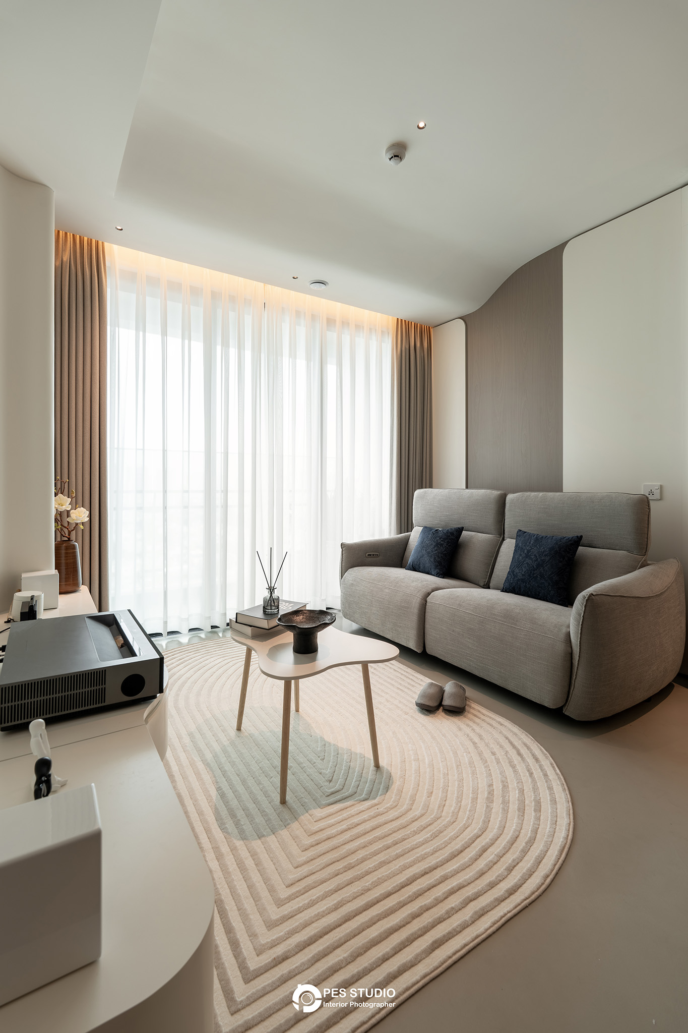Phòng khách căn hộ Feliz En Vista với sofa xám và rèm voan trắng