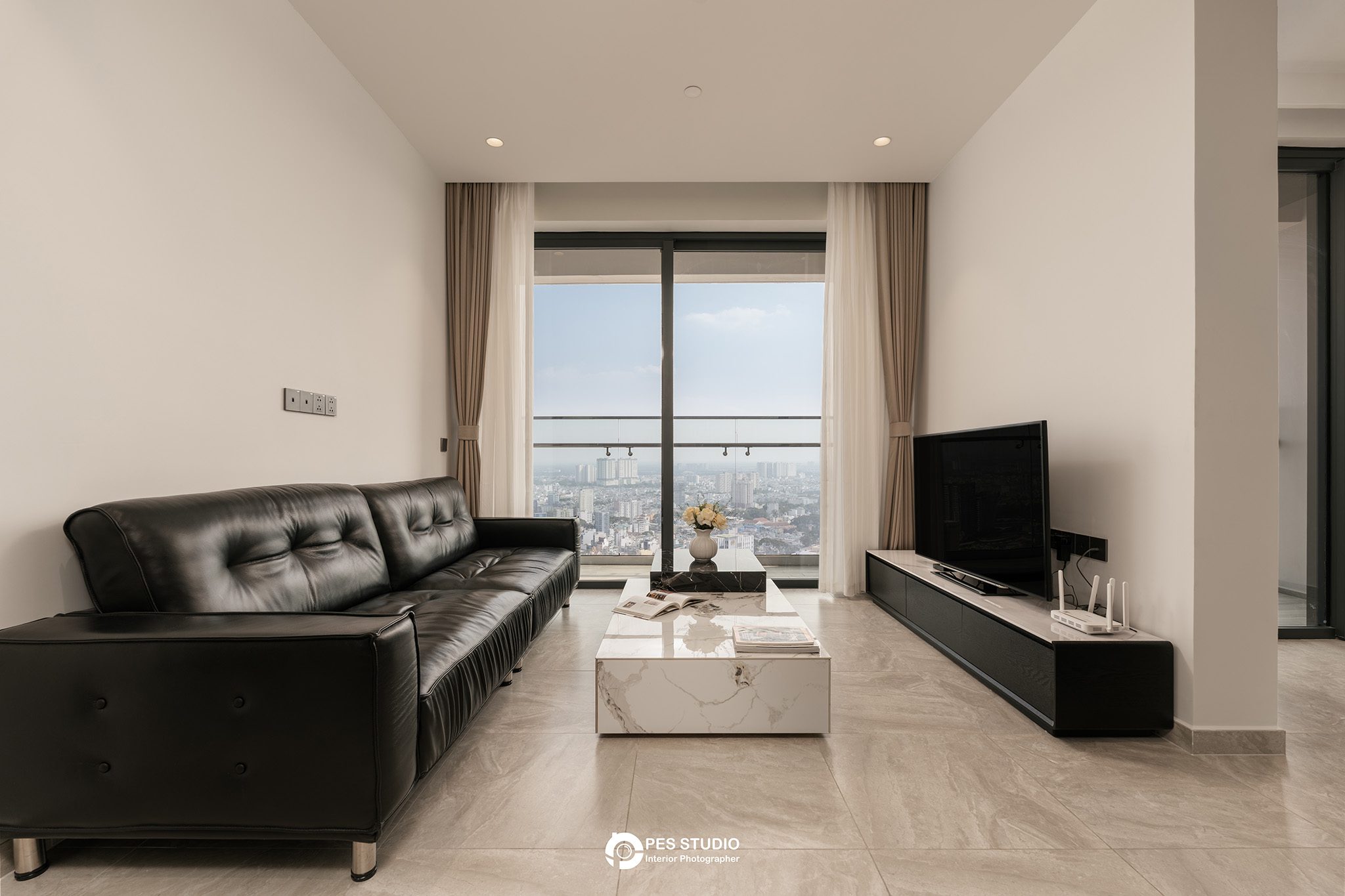 Phòng khách căn hộ Lancaster Legacy với sofa da đen và cửa kính lớn