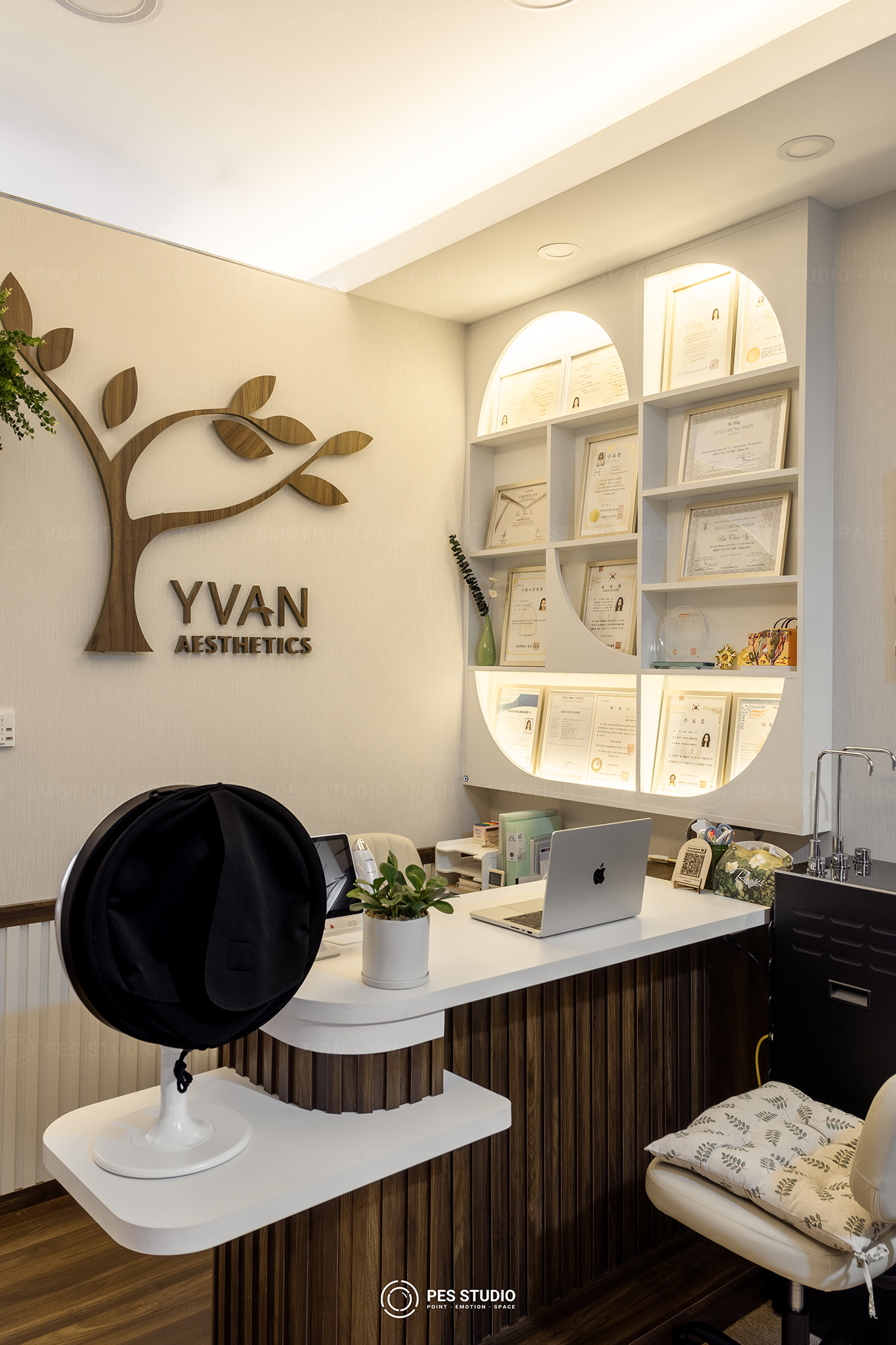 Quầy làm việc Yvan Aesthetics với hệ kệ vòm trắng và hình cây vẽ trên tường