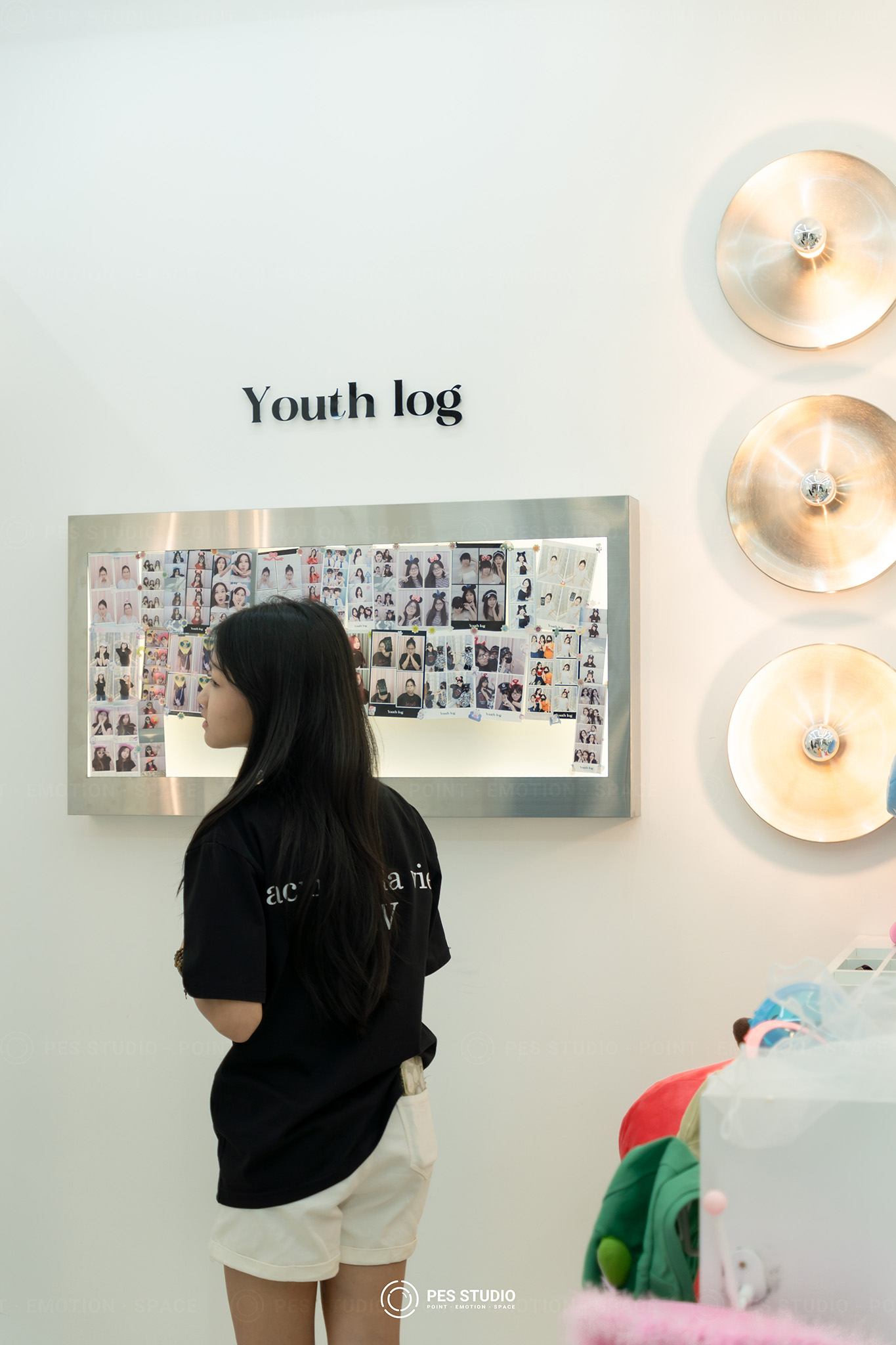 Khách nữ đứng xem tường mẫu ảnh Youth Log