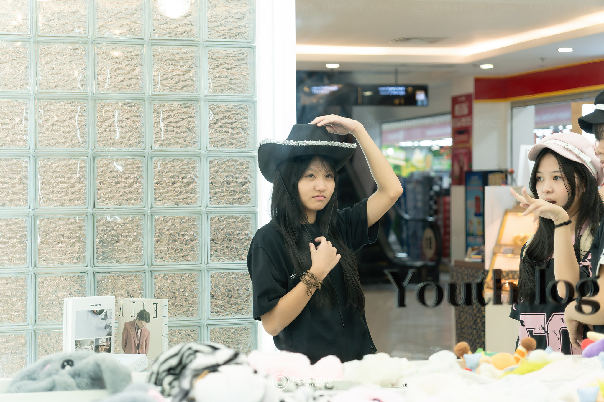 Khách nữ đội mũ đen tạo dáng trước vách gạch kính Youth Log