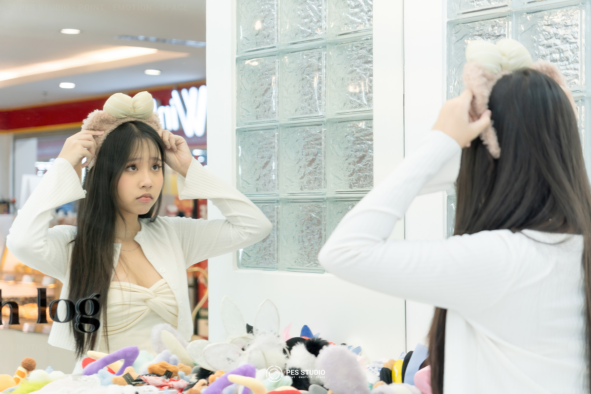 Hai khách nữ thử mũ trắng tại quầy phụ kiện Youth Log