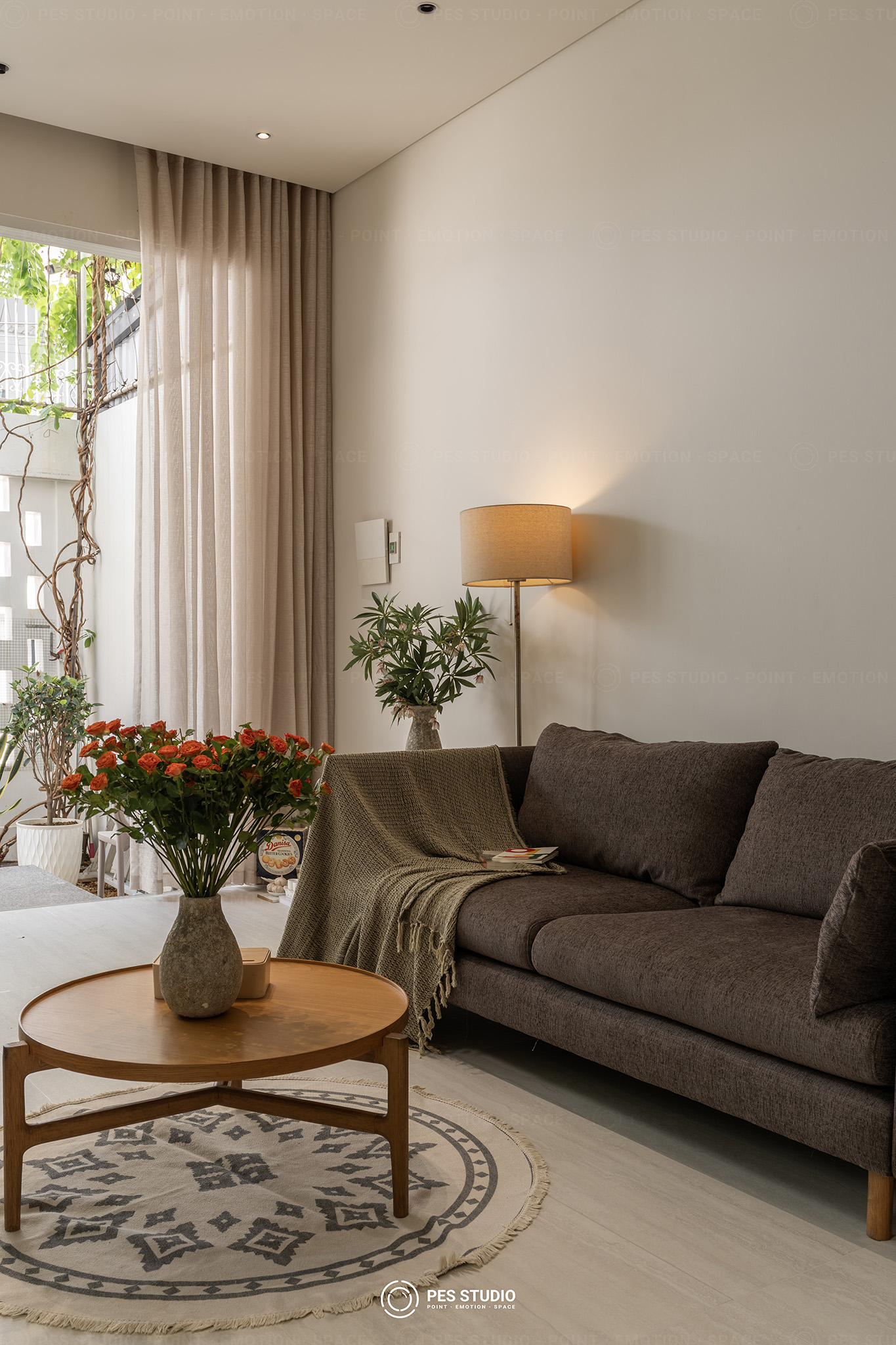 Bộ sofa xám và thảm tròn hoạ tiết trong phòng khách nhà phố