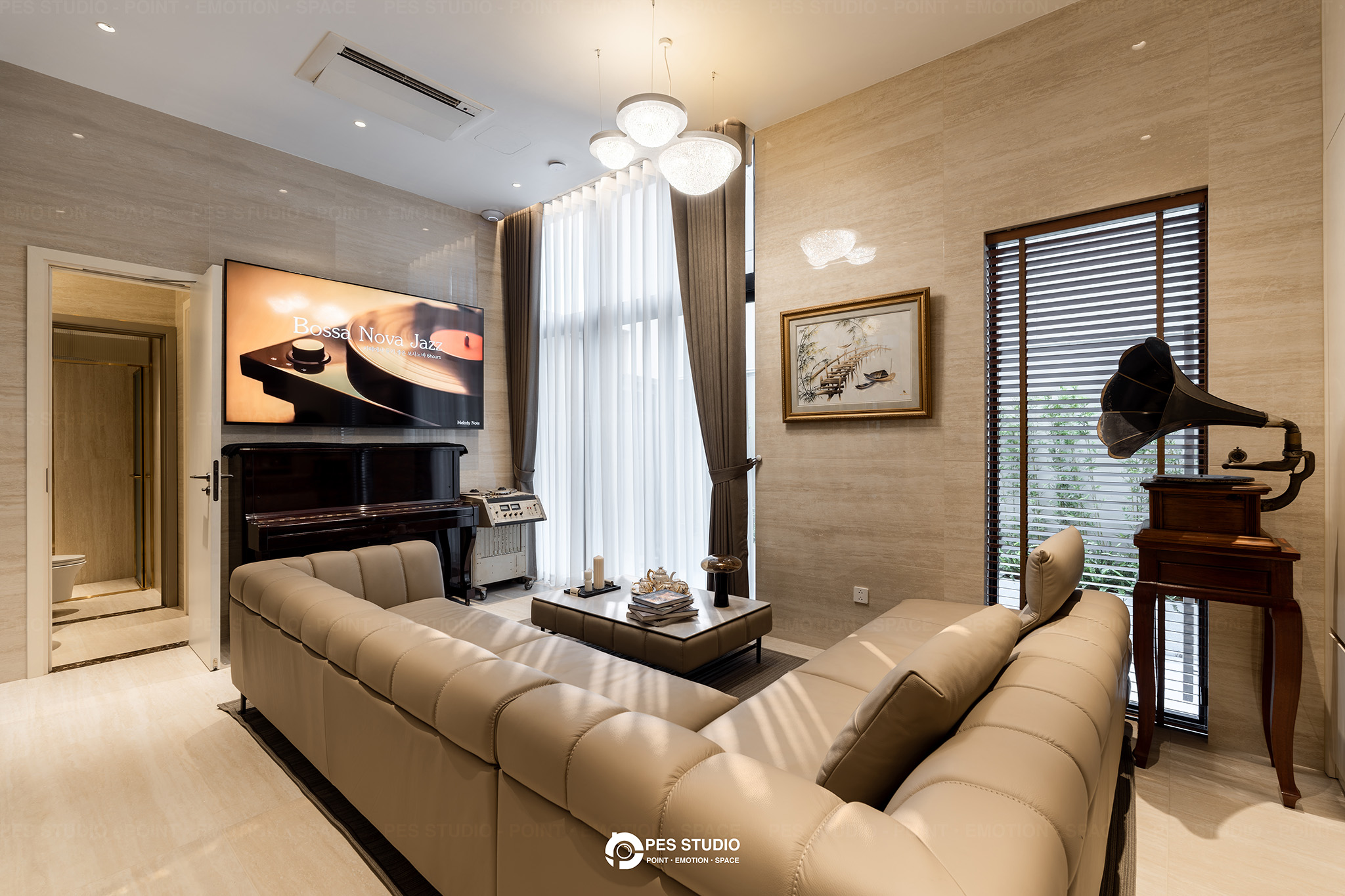 Phòng khách villa Sycamore với sofa da kem, đàn piano và tranh thuỷ mặc