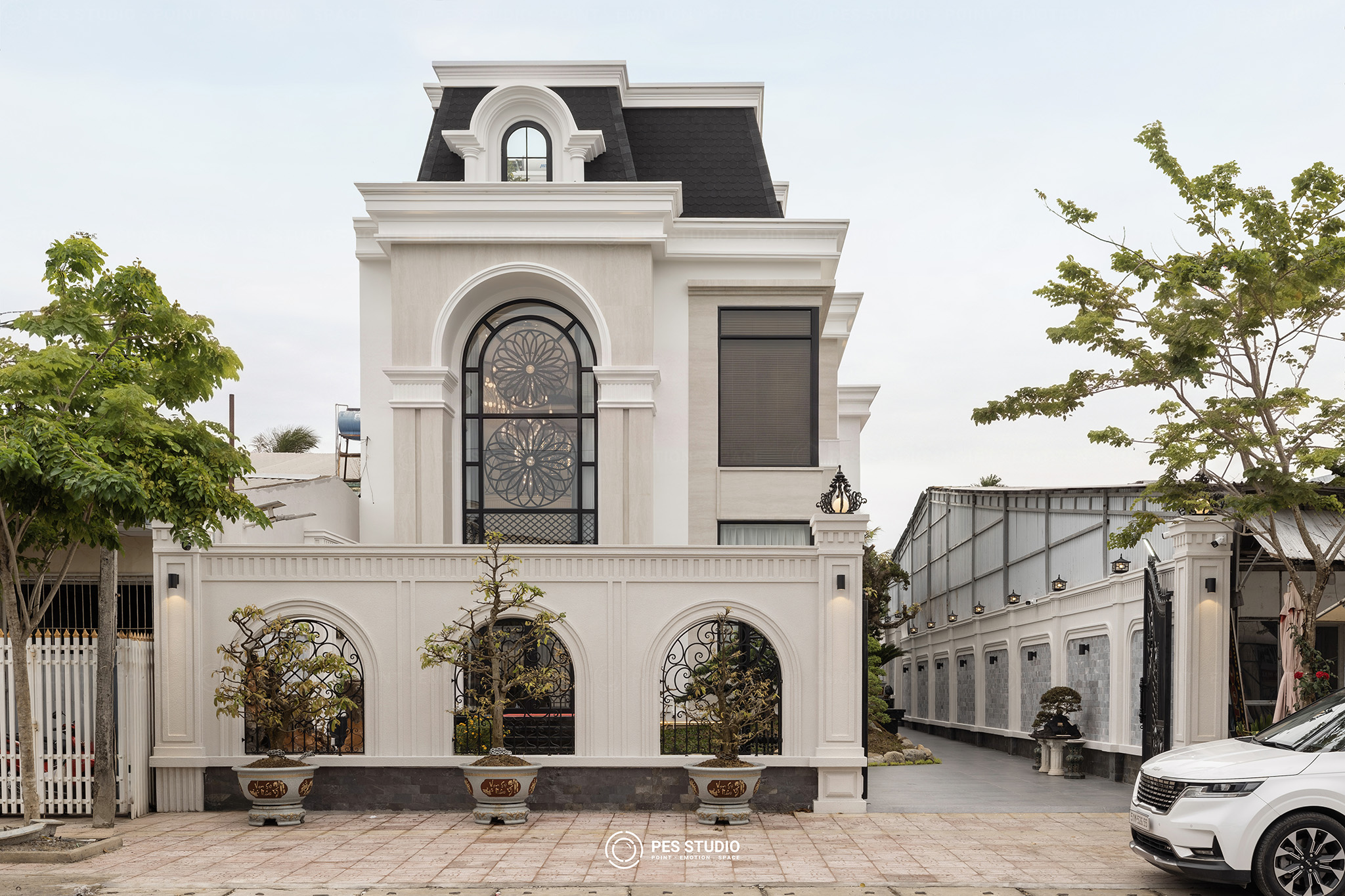 Mặt tiền villa tân cổ điển tại Vĩnh Long nhìn từ đường, tường rào ba vòm cuốn và chậu bonsai