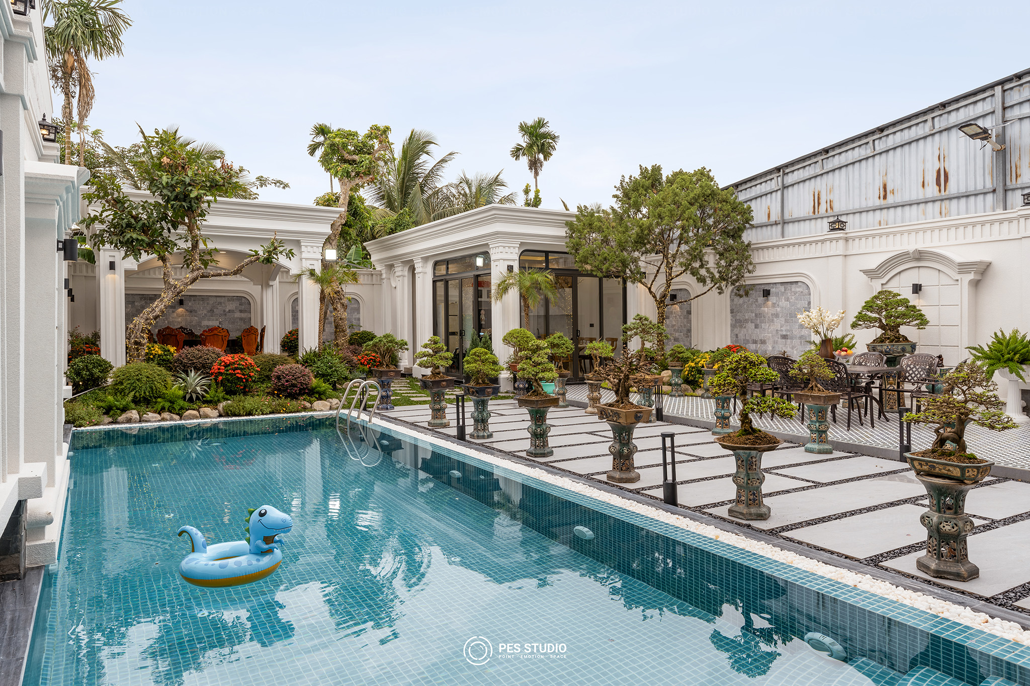 Sân trước villa với lối đi lát đá và cây cảnh tạo hình