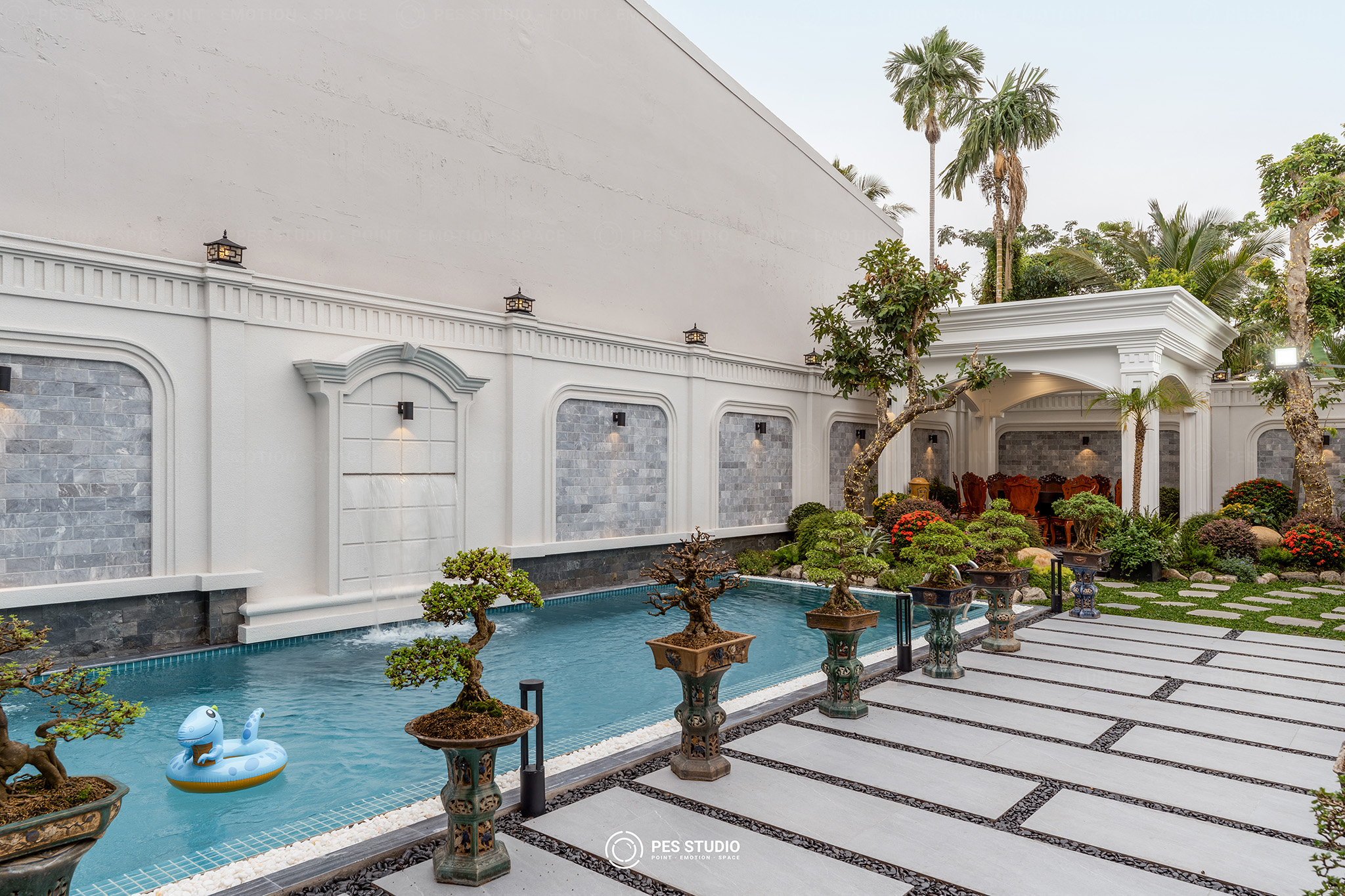 Sân trong villa với bộ bàn ghế gang đúc và cây thông trang trí đèn