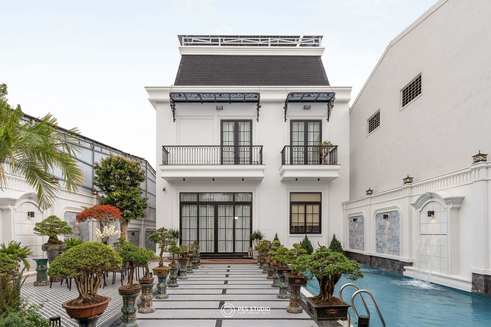 Mặt sau villa tân cổ điển nhìn từ hồ bơi, ban công sắt uốn và mái đón hoa sắt