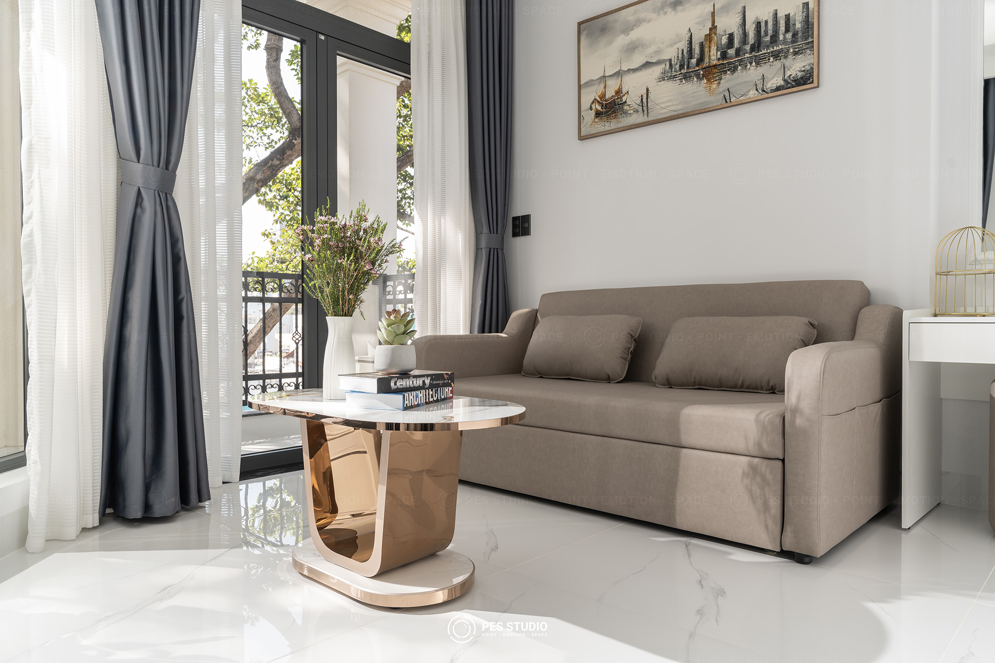 Phòng studio J.Stay với sofa be, bàn trà đá và cửa sổ cao sát trần