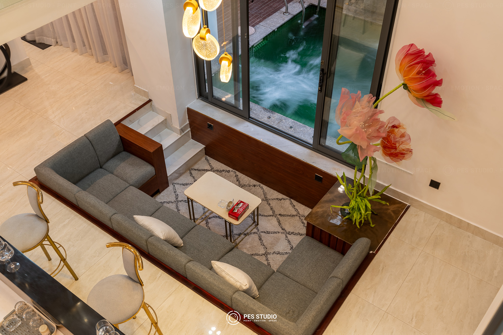 Phòng khách villa nhìn từ tầng lửng xuống bộ sofa xám và tranh hoa khổ lớn