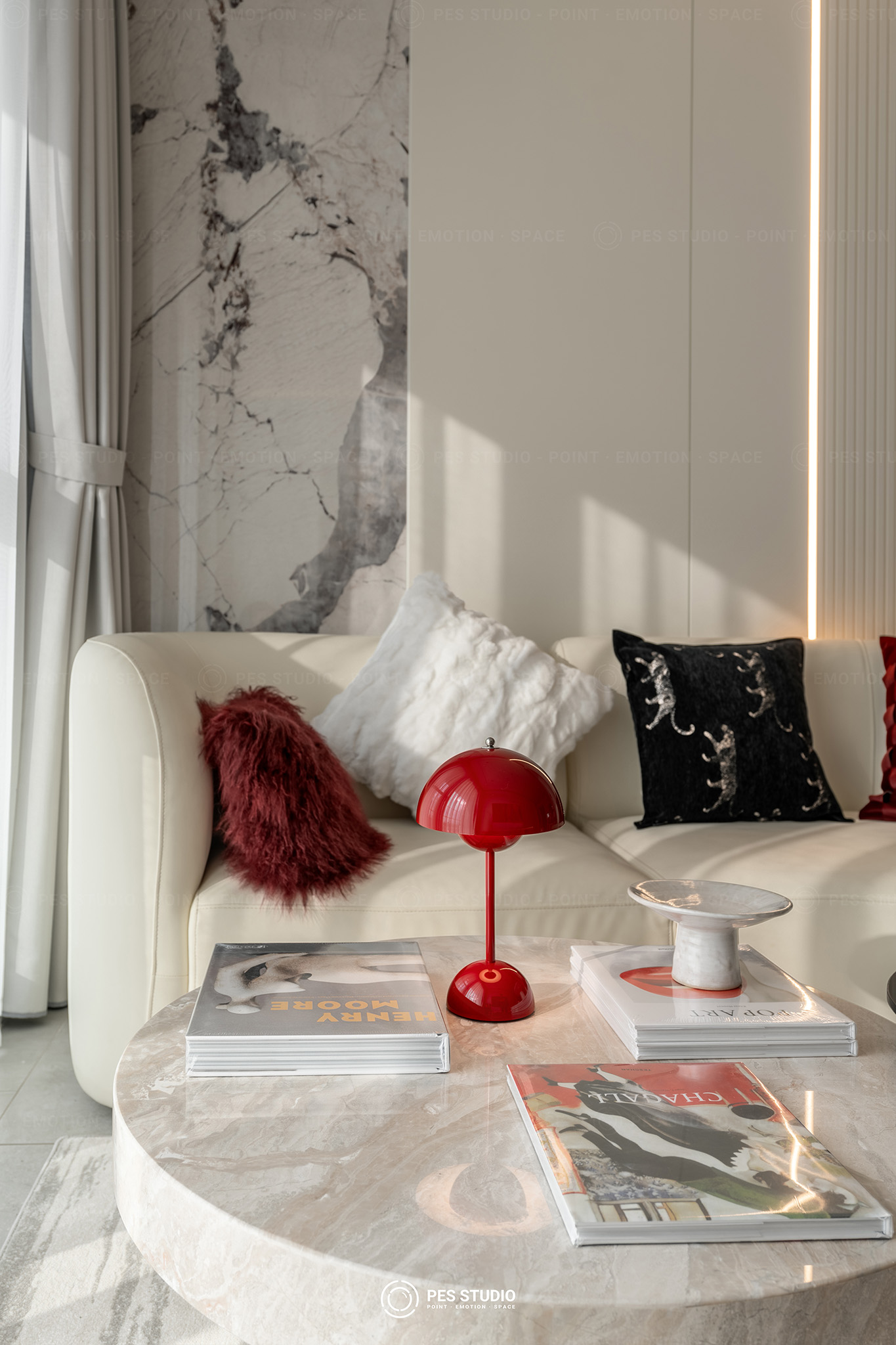 Góc sofa căn hộ Antonia với đèn bàn đỏ và mảng tường ốp đá vân xám