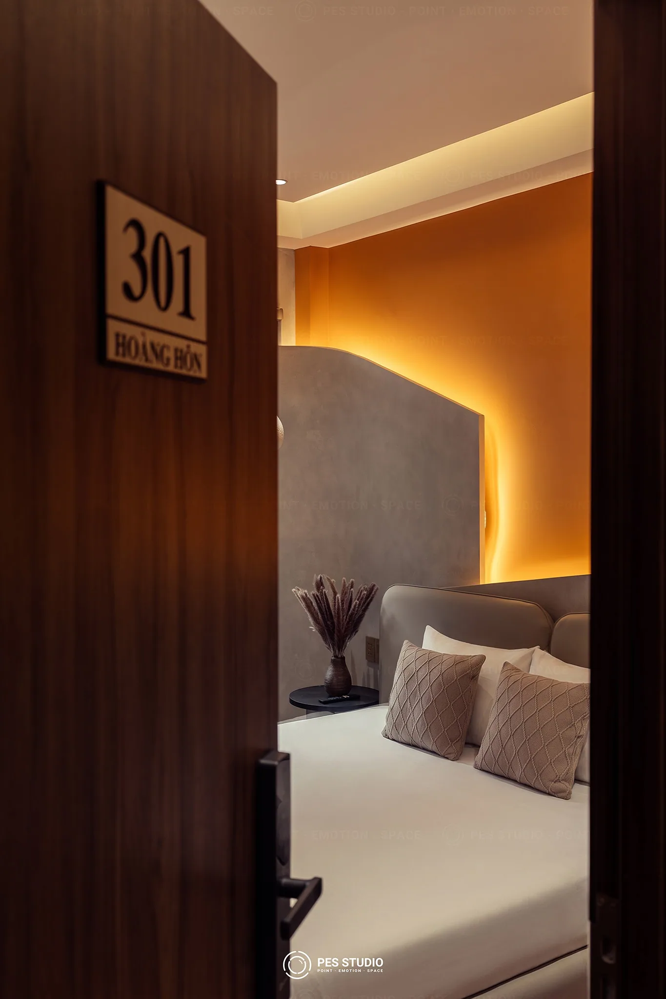 Cửa phòng 301 Hoàng Hôn hé mở tại Cô Hai Homestay Mỹ Tho, mảng tường cam đất hắt sáng phía sau