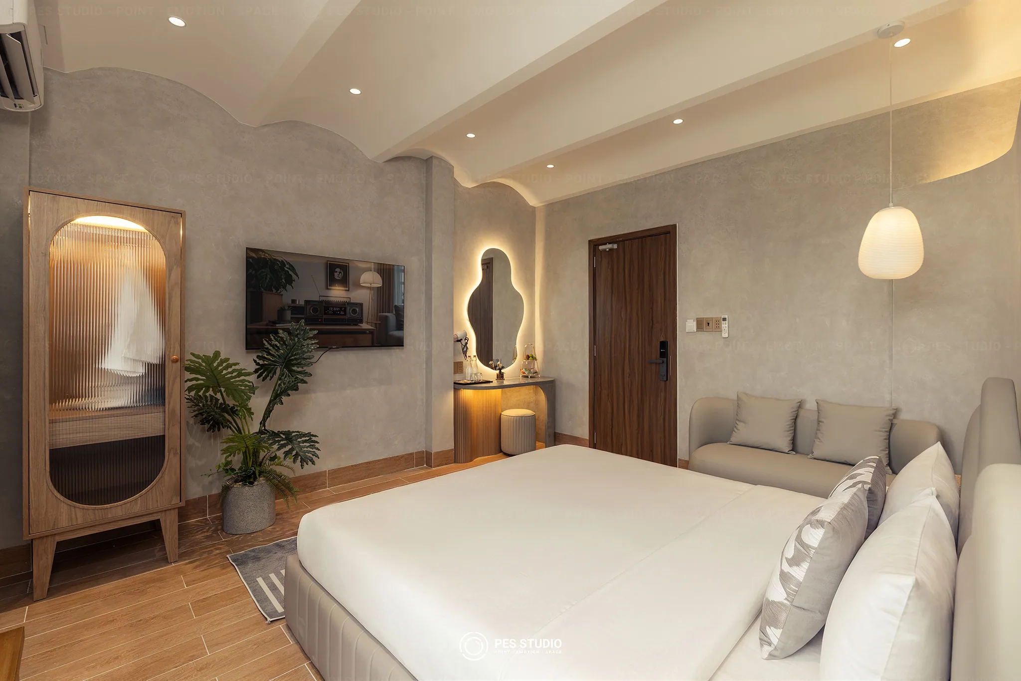 Góc sofa và tủ gỗ cánh kính lượn sóng trong phòng ngủ Cô Hai Homestay Mỹ Tho