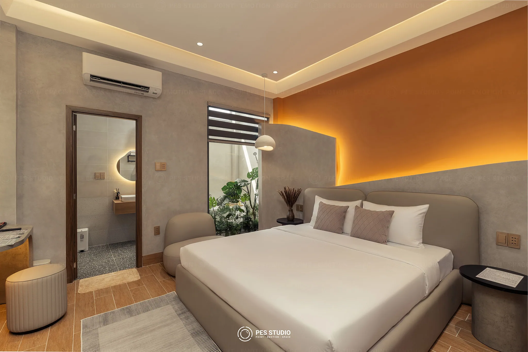 Phòng ngủ mảng tường cam đất hắt sáng tại Cô Hai Homestay Mỹ Tho, đầu giường bọc da và cây xanh