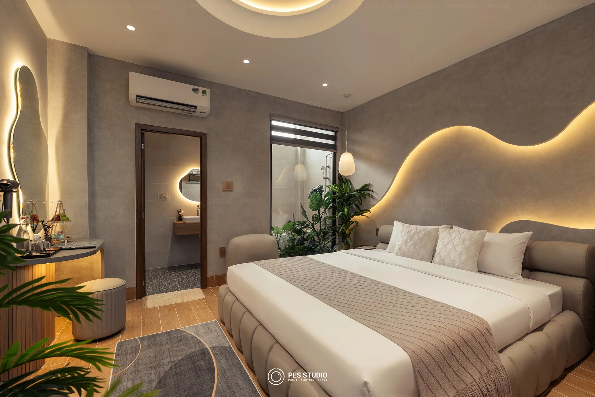 Phòng ngủ Cô Hai Homestay Mỹ Tho nhìn từ cửa, tường lượn sóng hắt đèn và giếng trời cây xanh cạnh phòng tắm